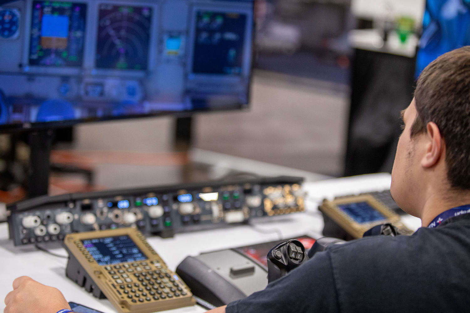 An attendee experiencing an airliner cockpit on the FlightSimExpo show floor.
