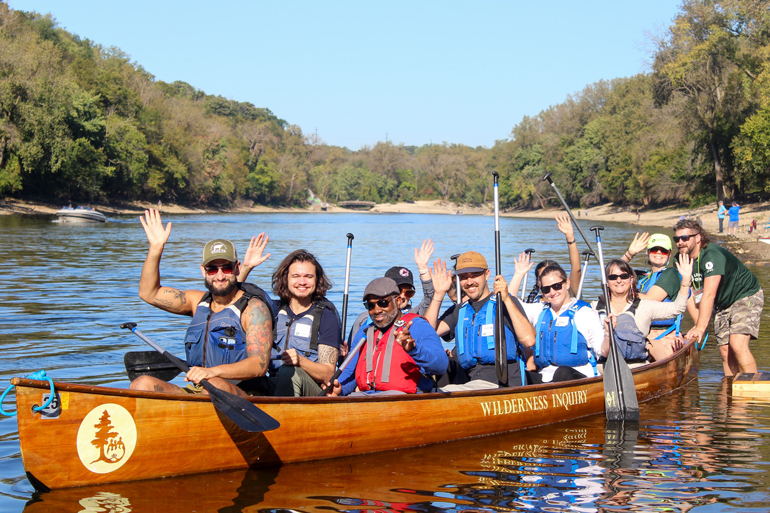 A group waving and smiling from a canoe.